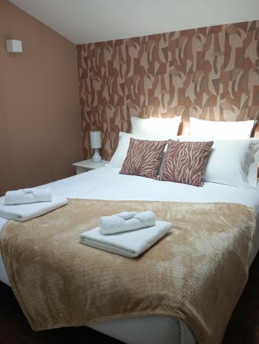 a bedroom with a large bed with two towels on it at Le Familia in Guer