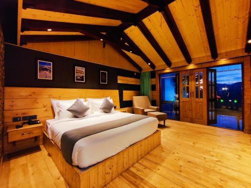 a bedroom with a large bed in a room with wooden walls at Regenta Resort MARS Valley View Shoghi in Shimla