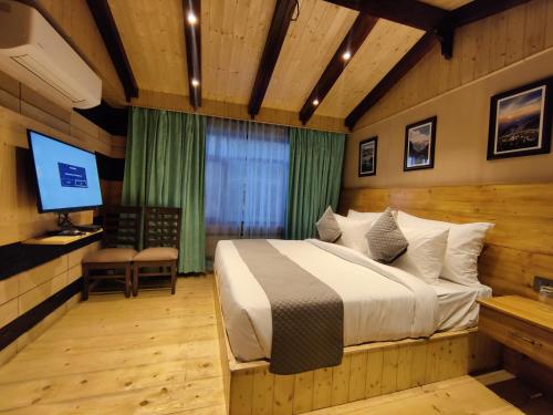 a bedroom with a bed and a television in it at Regenta Resort MARS Valley View Shoghi in Shimla