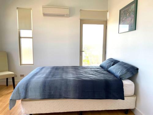 a bed with a blue comforter in a bedroom at Kinroc House in Port Moonta