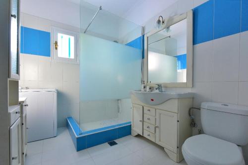 a blue and white bathroom with a toilet and a sink at Limnionas Bay Village Hotel in Marathokampos