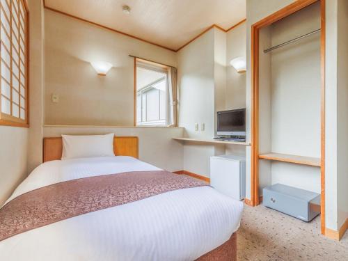 a small bedroom with a bed and a tv at KAMENOI HOTEL Akita Yuze in Kazuno