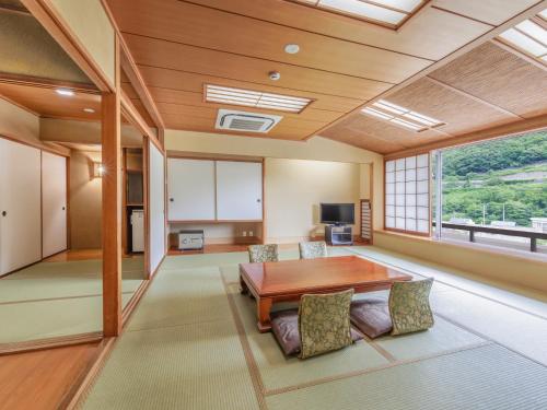 a living room with a table and a large window at KAMENOI HOTEL Akita Yuze in Kazuno