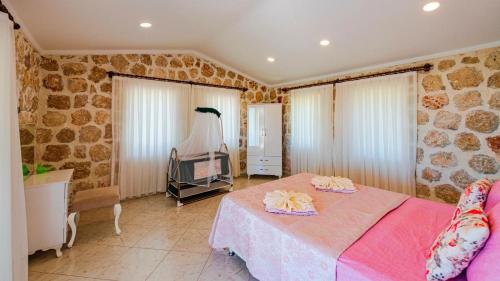 a bedroom with a pink bed and a stone wall at Villa atılgan in Kaş