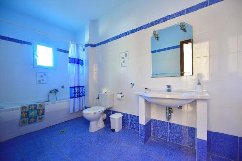 a blue and white bathroom with a sink and a toilet at Limnionas Bay Village Hotel in Marathokampos