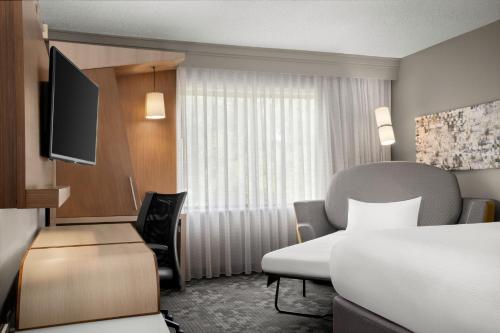 a hotel room with a bed and a television at Courtyard Lafayette Airport in Lafayette