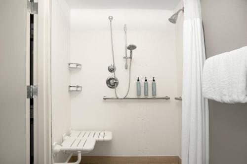 a white bathroom with a bench and a shower at Courtyard Lafayette Airport in Lafayette