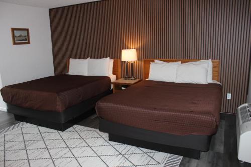 a hotel room with two beds and a table with a lamp at Cedarwood Inn of Ashland in Ashland