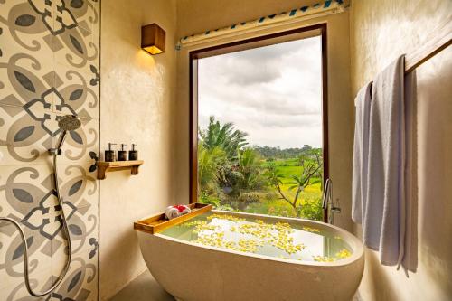 a bath tub in a bathroom with a window at Bliss Ubud Spa Resort in Ubud