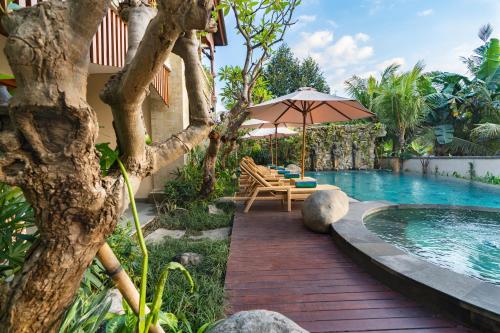 a pool with chairs and an umbrella next to a house at Bliss Ubud Spa Resort in Ubud