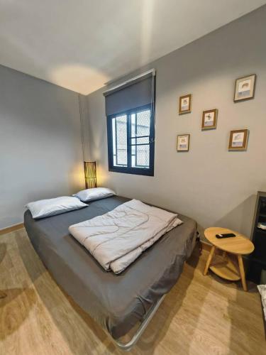 a bedroom with a bed with a window and a table at 57 Hidden House BKK Chinatown in Bangkok