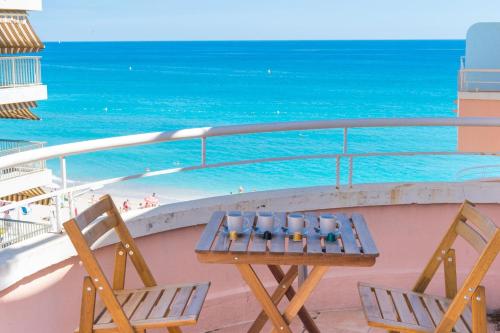 ein Tisch und zwei Stühle auf einem Balkon mit Blick auf das Meer in der Unterkunft Gloria marris in Menton