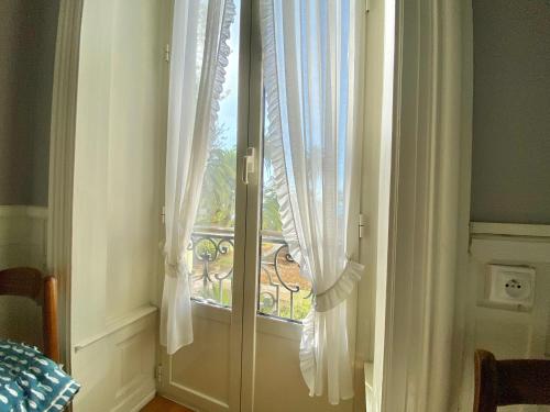 Cette chambre dispose d'une fenêtre avec des rideaux blancs. dans l'établissement 'Le Regina', Vue Mer, Plein Centre, Unique, à Menton