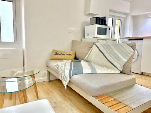 un salon avec un canapé et une table en verre dans l'établissement « Studio Cosy vieille ville » refait à neuf, à Menton