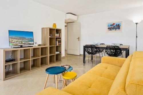 un salon avec un canapé jaune et une table dans l'établissement Splendide 2 pièces Vue Jardin, Calme, Plein Centre, à Menton