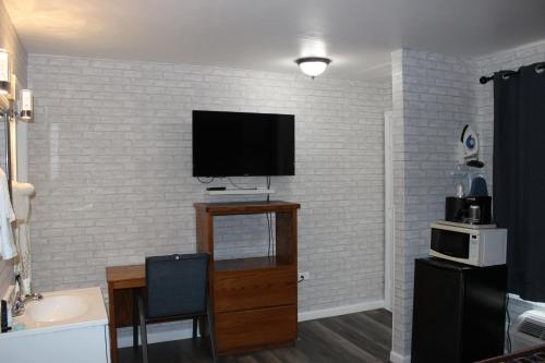a living room with a tv on a brick wall at Cedarwood Inn of Ashland in Ashland