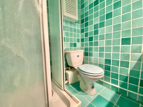 La salle de bains est pourvue de toilettes et de carrelage bleu. dans l'établissement Le Brea cosy studio dans la vieille ville, à Menton