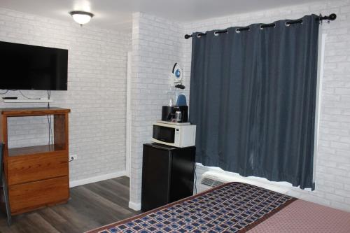 a room with a bed and a tv and a curtain at Cedarwood Inn of Ashland in Ashland