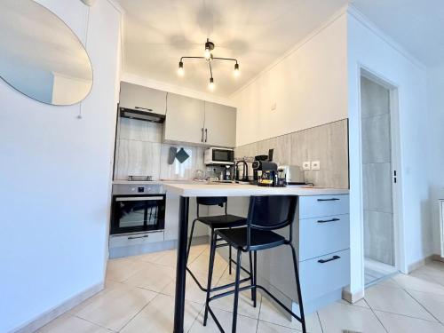 une cuisine avec des armoires blanches et un comptoir avec des tabourets dans l'établissement 'La Villa Melanie' Neuf, Equipé, Terrasse, Centre, à Menton