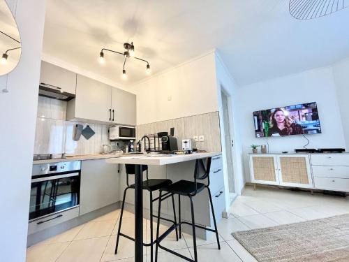 Il comprend une cuisine avec une table et une télévision murale. dans l'établissement 'La Villa Melanie' Neuf, Equipé, Terrasse, Centre, à Menton