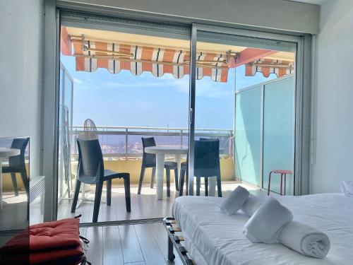 une chambre avec un lit et un balcon avec une table et des chaises dans l'établissement Le diplomat, vue mer, cosy, à Menton