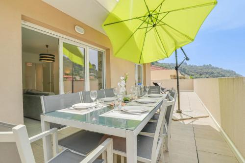 - une table à manger avec un parasol jaune sur la terrasse dans l'établissement Spacieux Rooftop Parking, Terrasse ensoleillée, à Menton