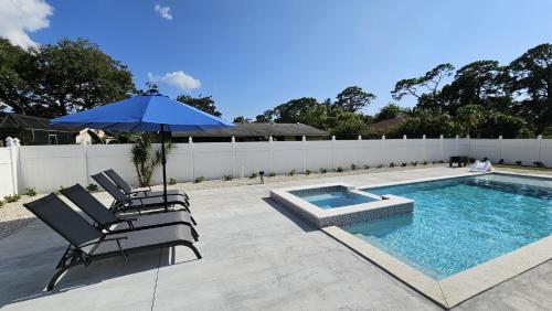 a swimming pool with two chairs and an umbrella at Luxury 3BD house, Siesta Key Beach in Sarasota