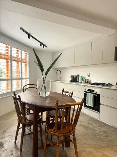a kitchen with a wooden table with chairs and a vase on it at The Paarl Grand in Paarl