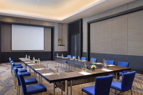 a meeting room with long tables and blue chairs at Le Meridien Chiang Rai Resort, Thailand in Chiang Rai