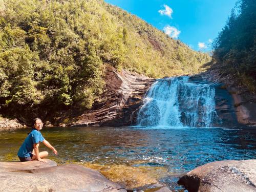 a person sitting on rocks in a river with a waterfall at maison Rose & Jardinier eco homestay in Sa Pa