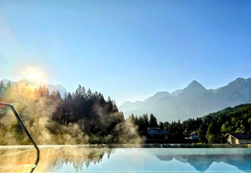 a swimming pool with mountains in the background at Hotel Lärchenhof in Lermoos