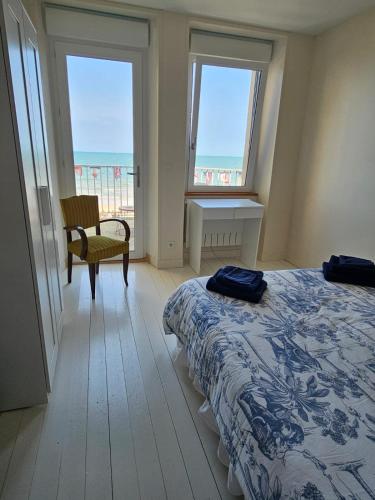 - une chambre avec un lit, une chaise et deux fenêtres dans l'établissement Villa Familia, à Grandcamp-Maisy