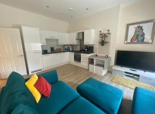 a living room with a blue couch and a kitchen at Queen Street Quayside Apartment, NE1 Grade 2 Listed in Newcastle upon Tyne