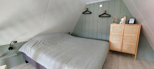 a small attic bedroom with a bed and a cabinet at Have a nice stay! - Trendy Vakantiehuis Carpe Diem met eigen tuin in Noordwijk