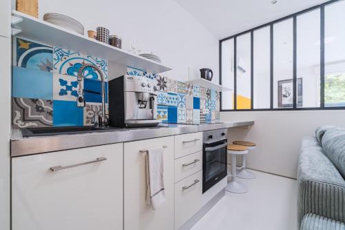 - une cuisine avec des placards blancs et du carrelage bleu et blanc dans l'établissement Le Minautore - Charmant studio climatisé, à Toulouse