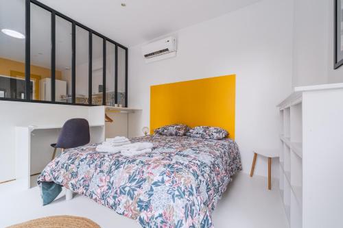 - une chambre avec un lit et un mur jaune dans l'établissement Le Minautore - Charmant studio climatisé, à Toulouse