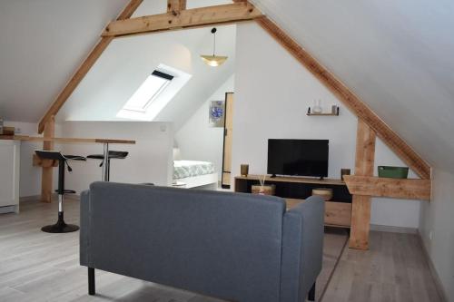 a living room with a couch and a tv at Bords de l'Aure, Meublé de tourisme 3 étoiles in Bayeux