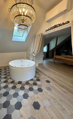 une grande salle de bains avec baignoire et lustre dans l'établissement Love room l escapade, à Guitrancourt