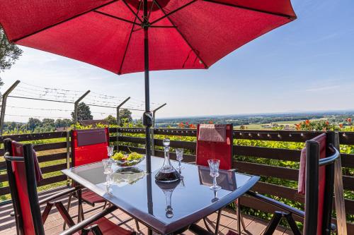 a table with wine glasses and an umbrella on a balcony at Holiday house VilAna with Jacuzzi - Happy Rentals in Puconci