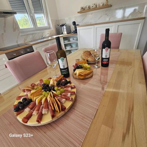 a table with a plate of food and two bottles of wine at Villa Hirundinidae in Gornji Muć