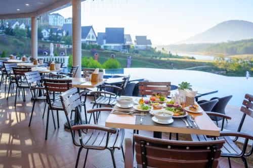 a restaurant with tables and chairs with a view of the water at Dalat Wonder Resort in Da Lat