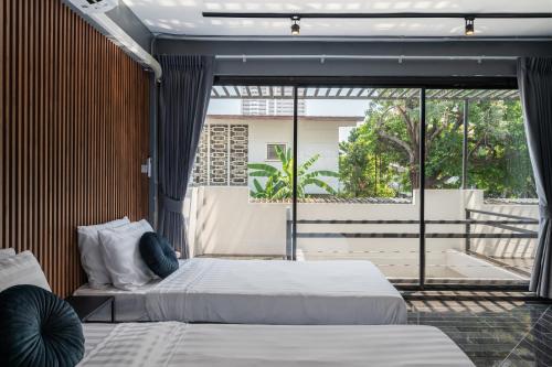 two beds in a room with a large window at S21 Mellow Phromphong in Bangkok