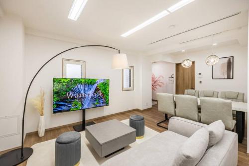 a living room with a couch and a tv on a wall at 渋谷駅電車1分 恵比寿駅徒歩2分 85平米最大6名 東京 新宿 上野 銀座 池袋 築地直通 in Tokyo