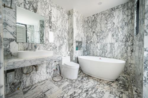 a bathroom with a tub and a toilet and a sink at S21 Mellow Phromphong in Bangkok