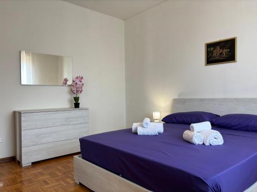 a bedroom with a bed with purple sheets and towels at Casa Aurelio 2 min dall'ospedale in Negrar