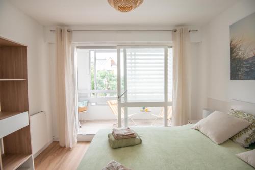 a bedroom with a bed and a large window at Face à Juno Beach - Appartement vue mer et port in Courseulles-sur-Mer