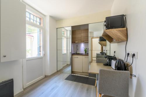 Il comprend une cuisine avec une table et une télévision murale. dans l'établissement Cozy Corner 77 - Appt avec jardin pour 4, à Tournan-en-Brie