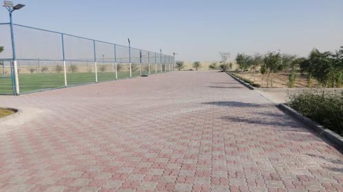 a long brick road with a fence in the background at Ace Arena Resort in Al Rahba