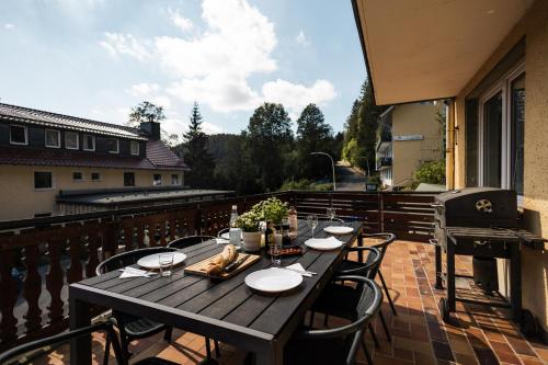 a wooden table and chairs on a balcony at Apartmenthaus am Waldrand- Küche - Frühstück - Balkon in Wildemann