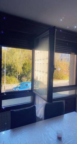 Cette chambre dispose de deux fenêtres, d'une table et de chaises. dans l'établissement Reims centre-ville -au1er étage avec 2 chambres - 6 personnes, à Reims